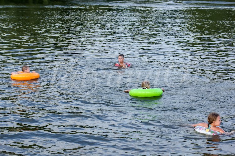 children swim with the inflatable circles in the river example image 1