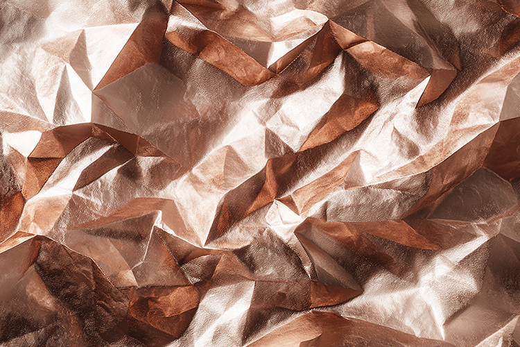A crumpled metallic surface with a rose gold color