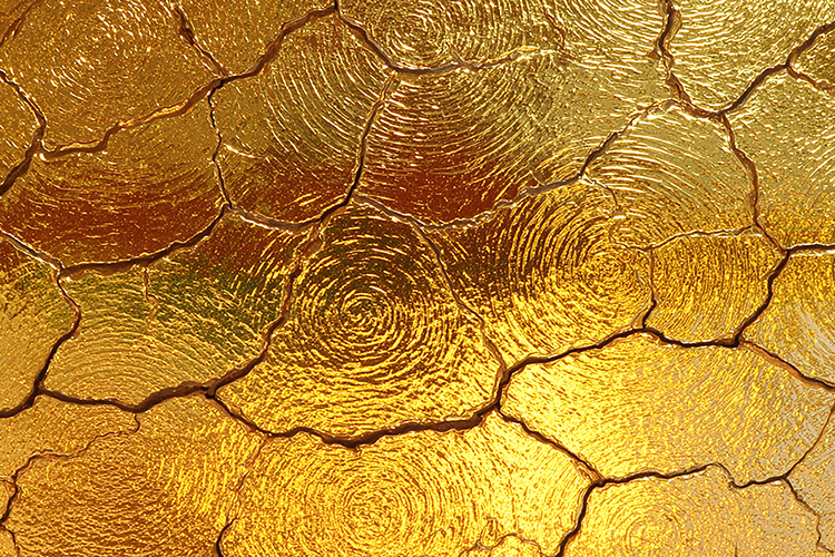 A cracked golden surface with a textured, spiral pattern