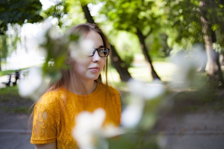 Beautiful girl in a glass stands between the flowers example image 1