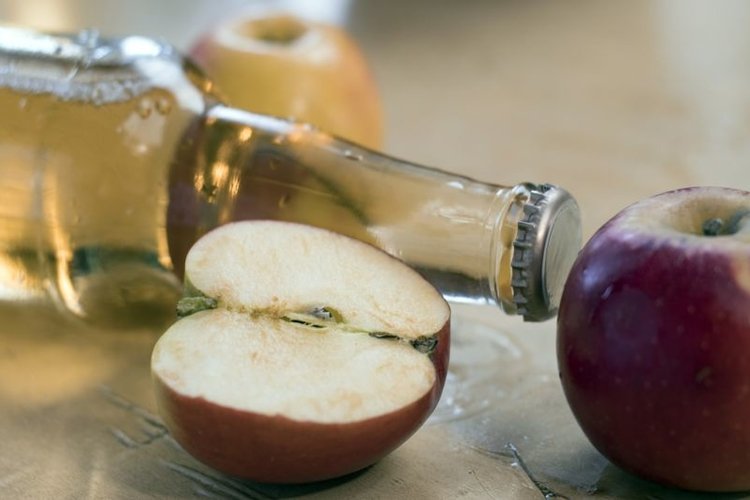 Glass bottle with a cider and apples on the table example image 1