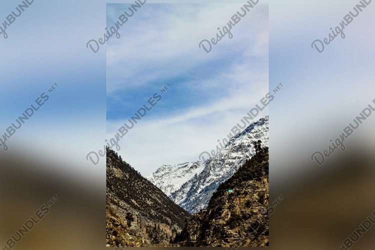 Vertical Shot of the mountains covered in snow under cloudy