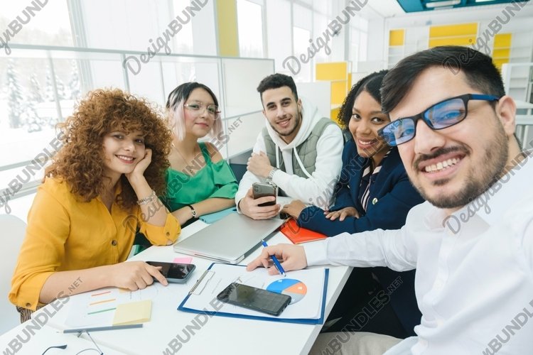 Self-portrait of cheerful business team at workplace