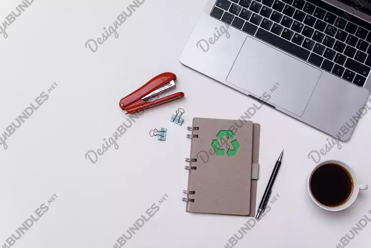 Notepad with zero waste sign next to laptop and stationery.
