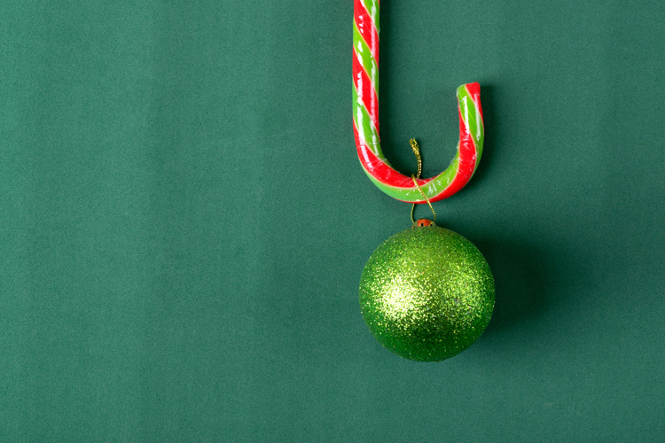 Glittering green bauble hanging on the candy cane