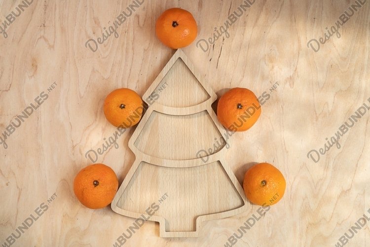Tangerines around a wooden plate in the form of a herringbon