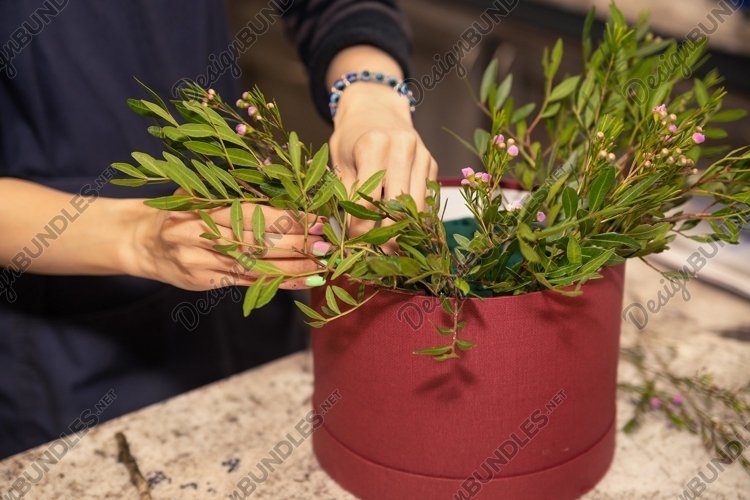Florist makes a flower composition in the hat box