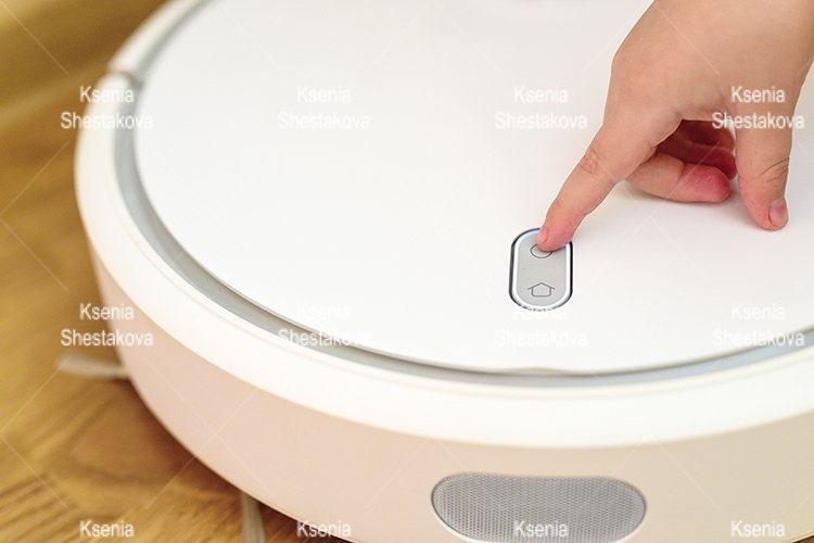 kids hand press button to turn the robot vacuum cleaner on