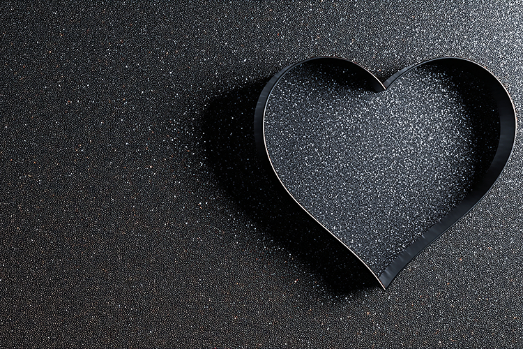 A heart-shaped cookie cutter on a dark textured surface