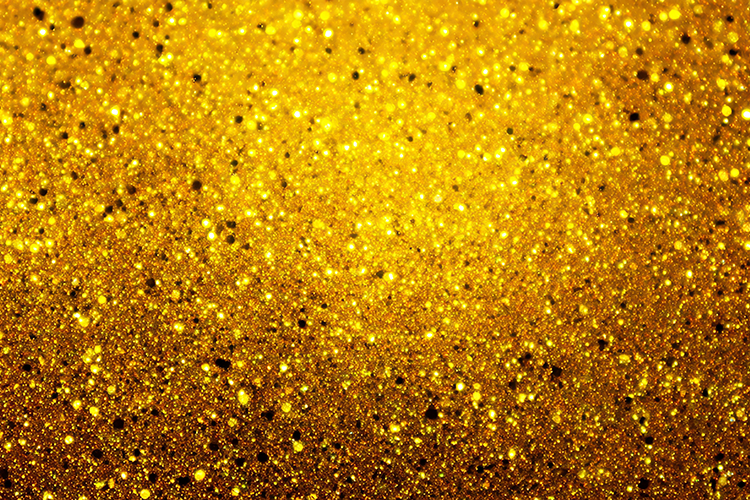 Gold glitter background with small black dots and sparkles