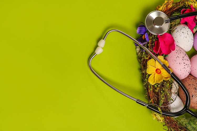 Medicine stethoscope with Easter eggs on green table
