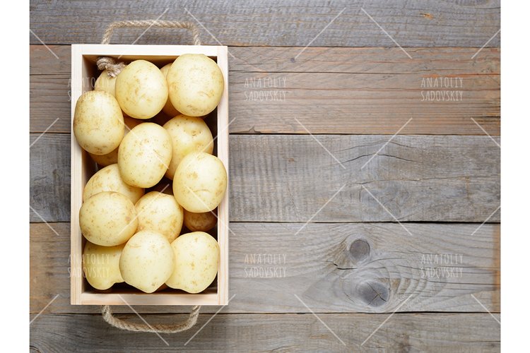Potatoes in wooden box on table top view