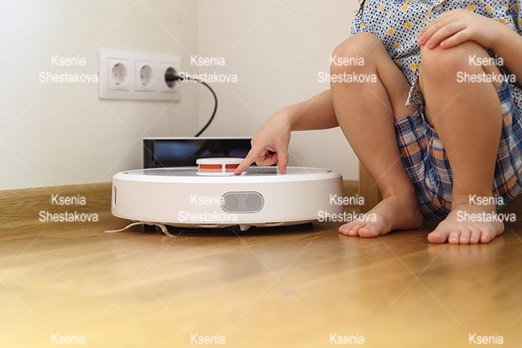 kids hand press button to turn the robot vacuum cleaner on