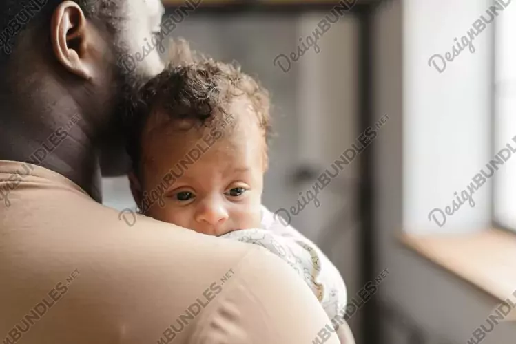 A young father is holding a baby. The eyes of a newborn baby