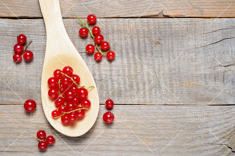 Red currant in wooden spoon on table example image 1