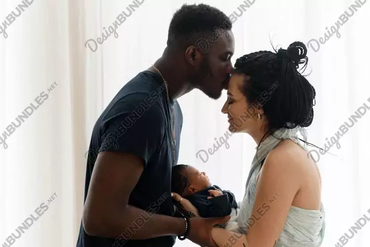 A black man kisses a wife and they hold their newborn baby