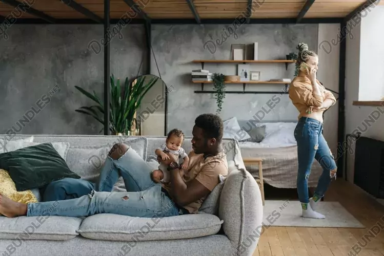 Father plays with baby while mother works from home
