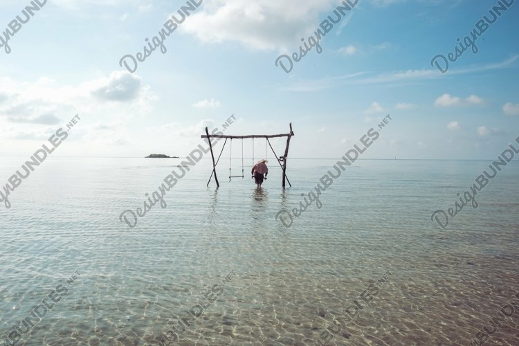 Lonely woman on wooden swing at sea shallow