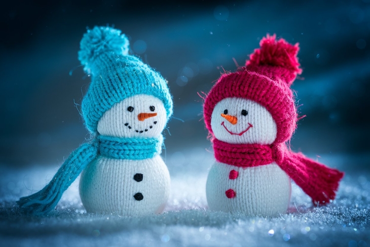 Two cheerful knitted snowmen wearing colorful hats