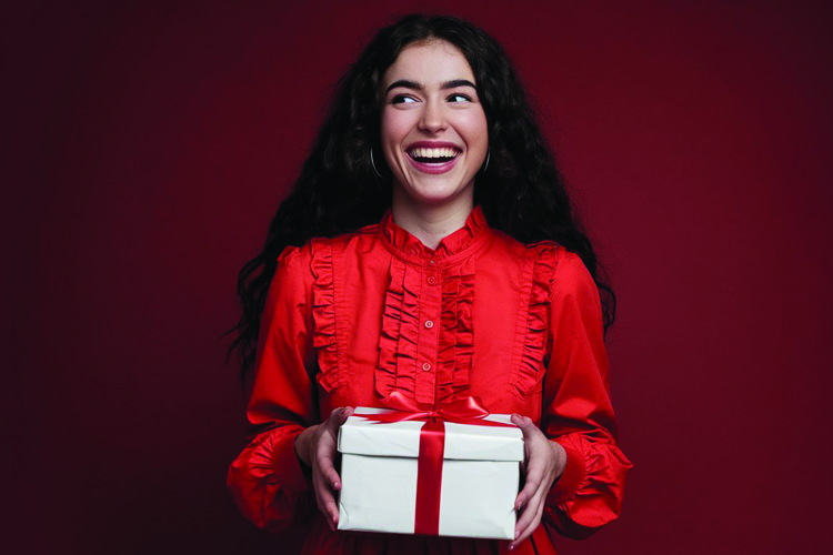 A red satin gift bow with golden edges on a black background