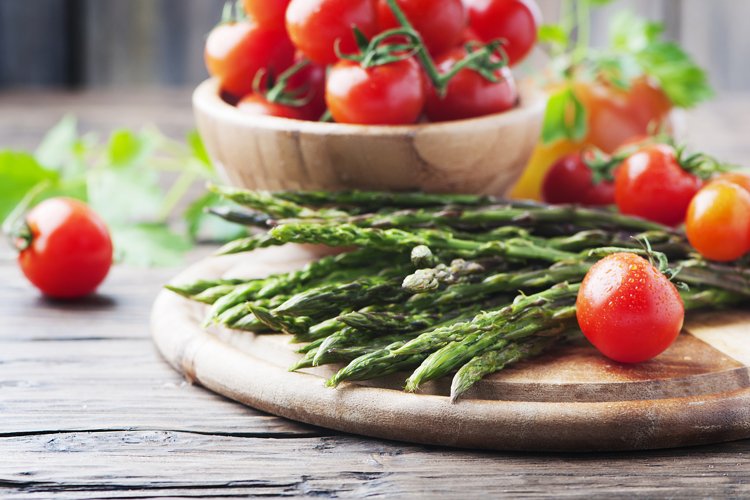 Uncooked asparagus with tomato on the wooden table