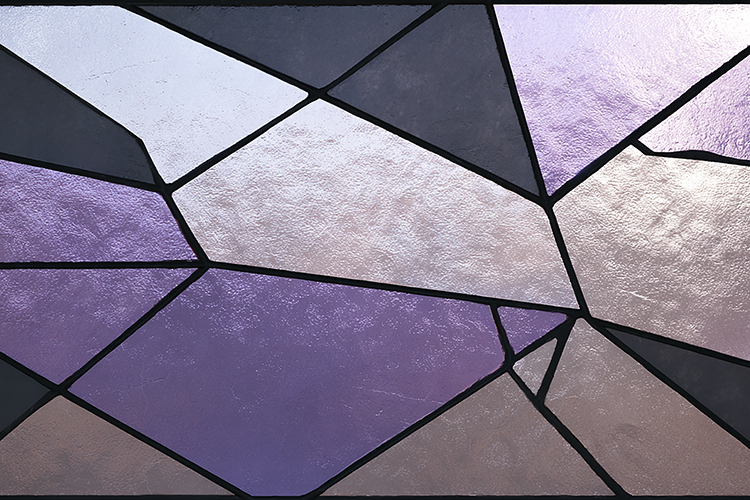 A stained glass window with purple and gray pieces