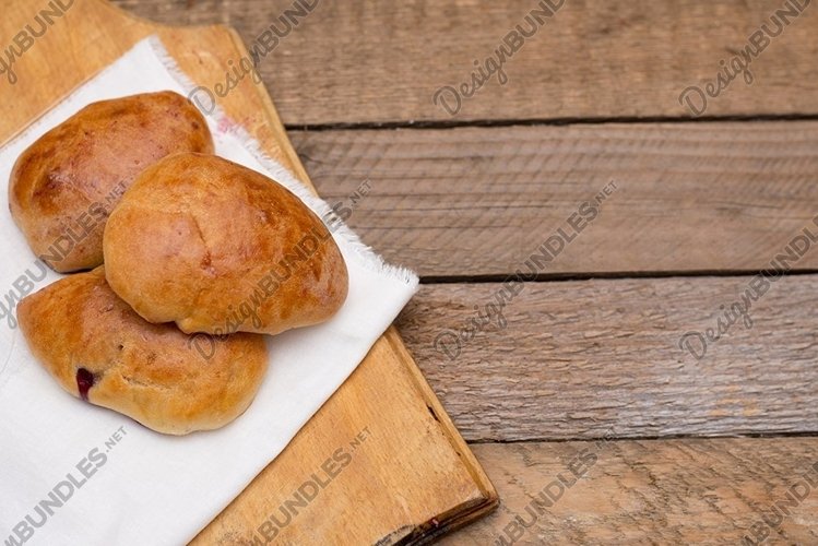 Russian pirozhki baked patties with berries on wood