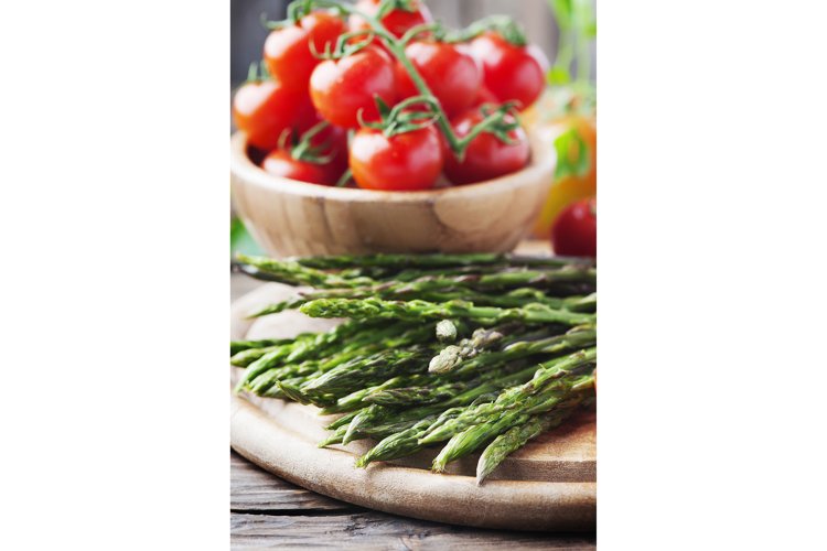 Uncooked asparagus with tomato on the wooden table example image 1