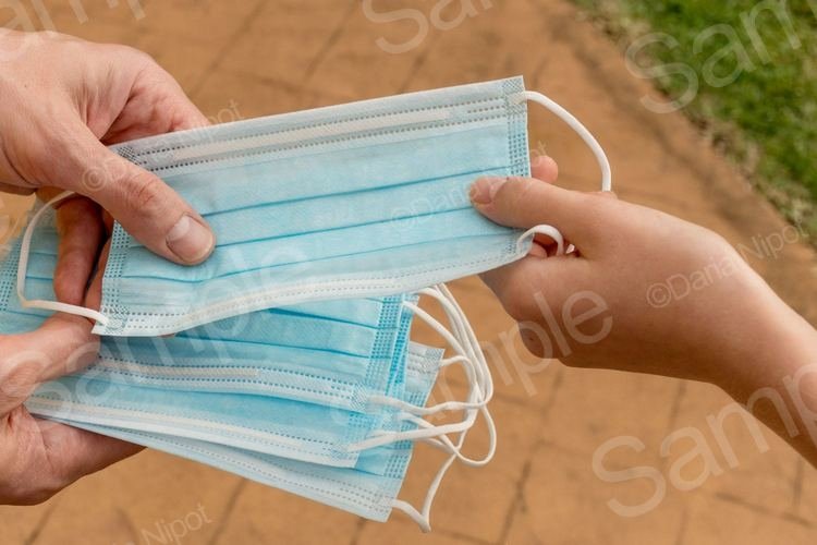 Hand holding and giving disposable face masks example image 1