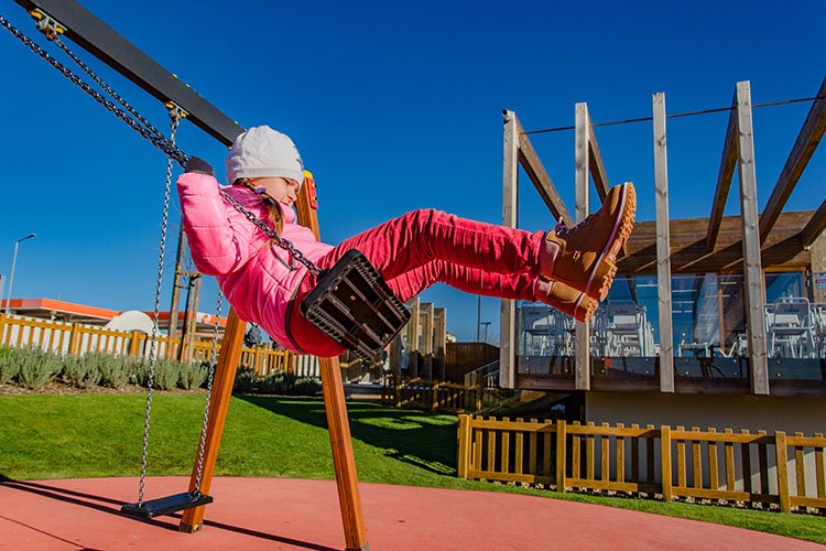 Little girl 5-6 years on a playground swinging on swing. example image 1