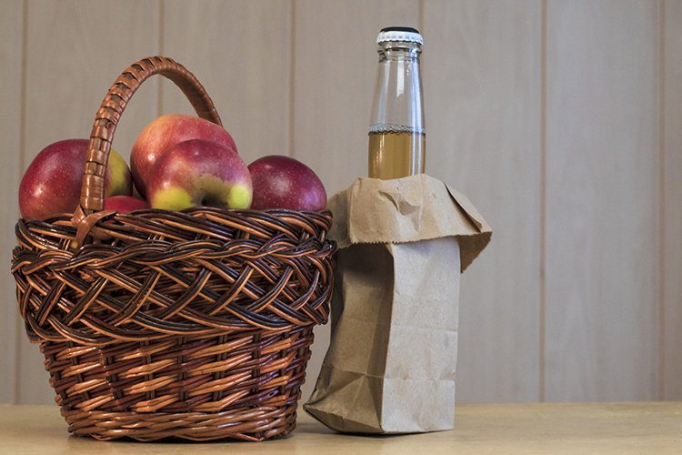 Glass bottle with a cider and apples in the basket example image 1