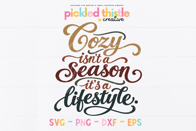 A hand-lettered digital cut file celebrating cozy season with flowing script, dramatic swashes, and warm autumn colours including mustard, rust, burgundy, and olive.