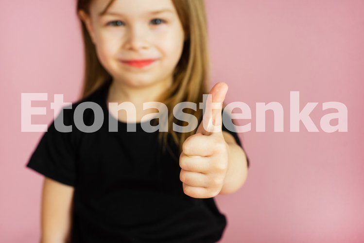 Little girl shows thumb up on a pink background example image 1