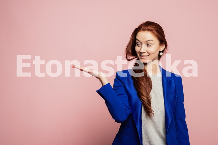 Woman showing pointing on pink background. example image 1