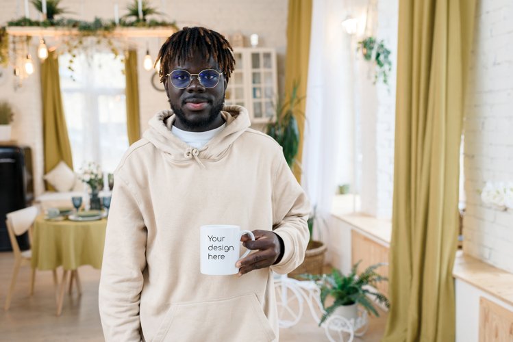 A white mug in the hands of a man in a home interior. example image 1