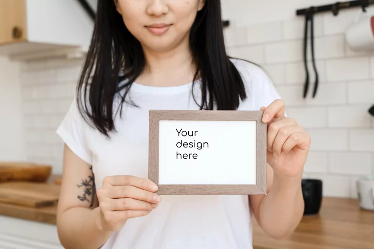 Asian woman holding white horizontal blank frame for design