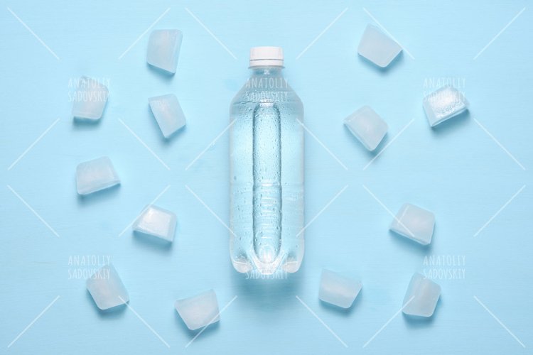 Water bottle and ice pieces on blue table top view