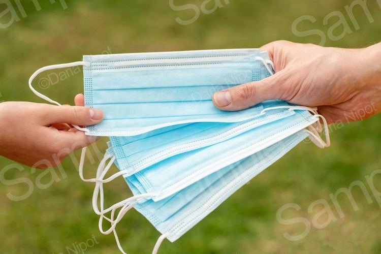 Hand holding and giving disposable face masks