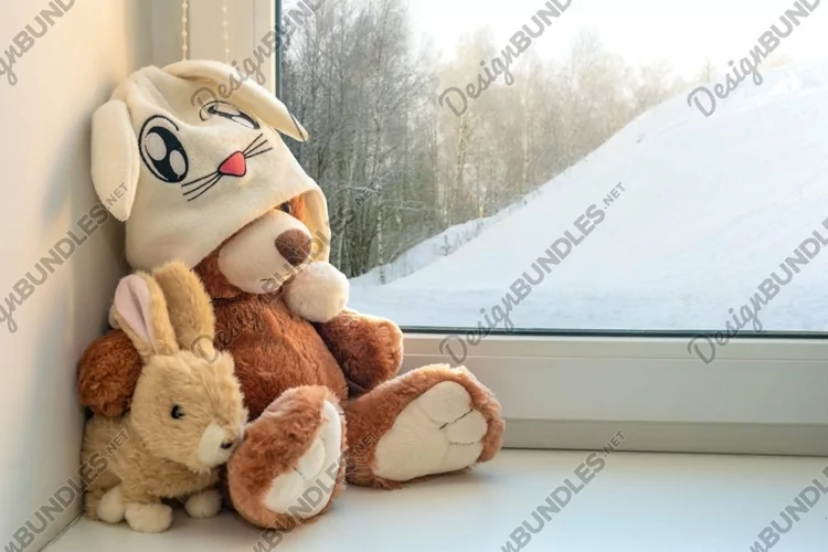 Teddy bear and bunny sits on window still. Winter, christmas