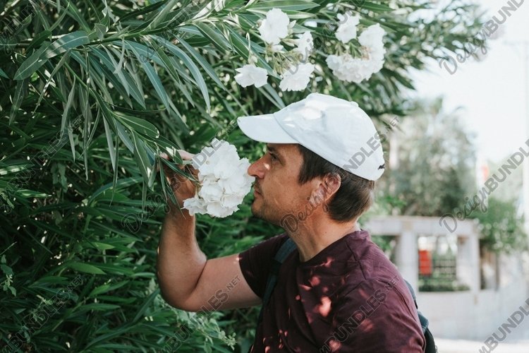 young candid man traveler enjoys the scent of a flowers