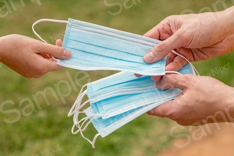 Hand holding and giving disposable face masks example image 1