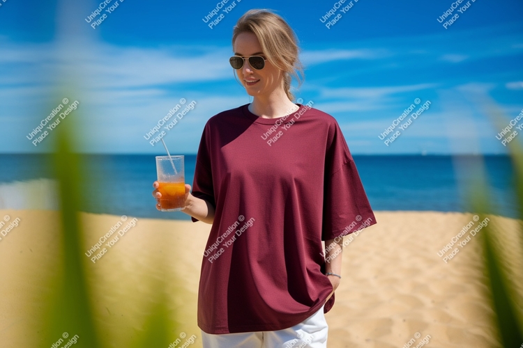 Woman wearing maroon t shirt holding orange drink on beach