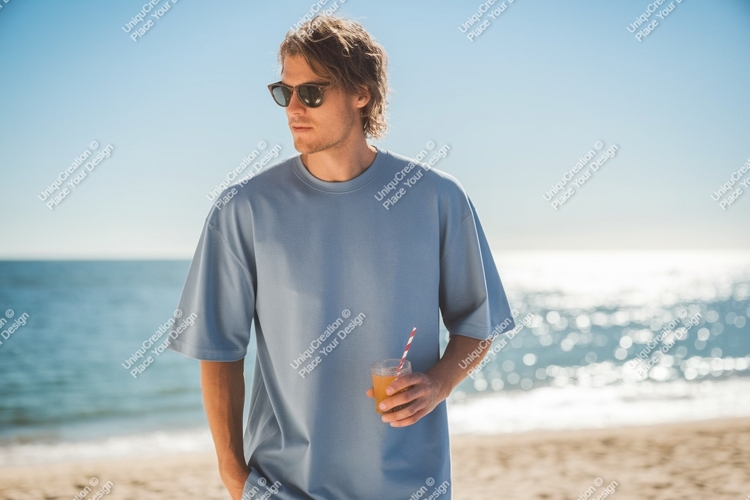 Man wearing blue shirt holding drink on beach image