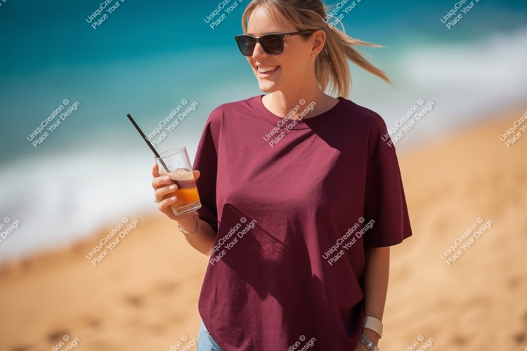 Woman wearing maroon t shirt holding drink on beach