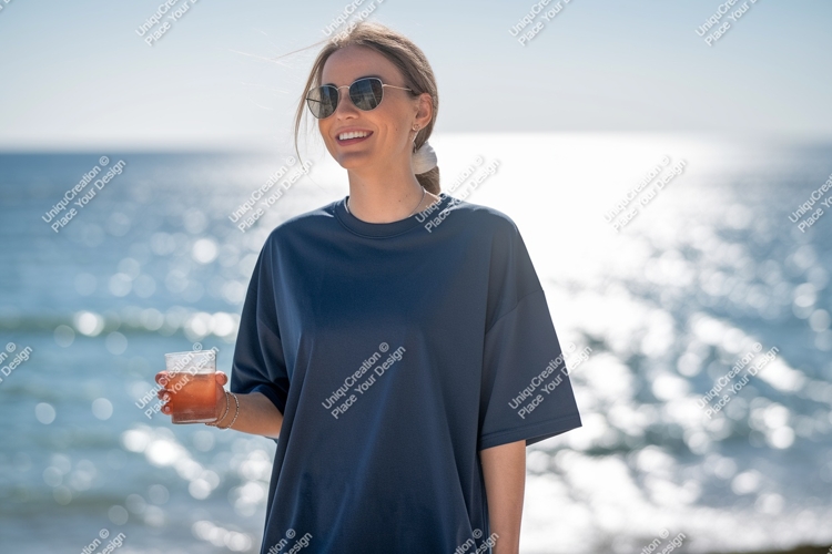 Woman wearing blue shirt holding drink by ocean image