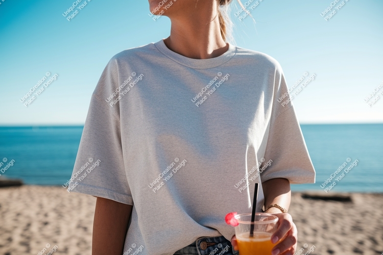 Woman wearing grey t shirt holding orange drink on beach