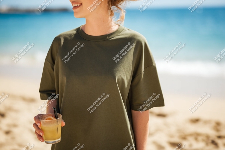 Woman wearing olive green t shirt holding drink on beach