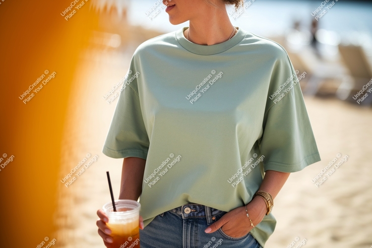 Woman wearing light green t-shirt holding drink beach