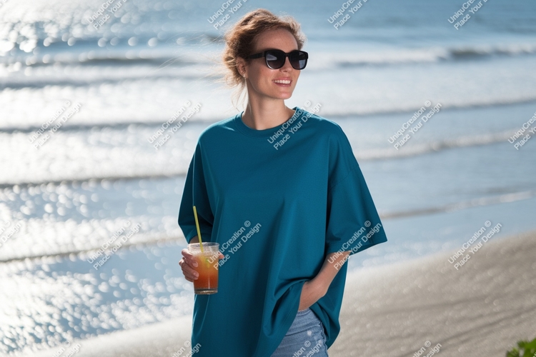 Woman wearing teal shirt holding drink at beach image