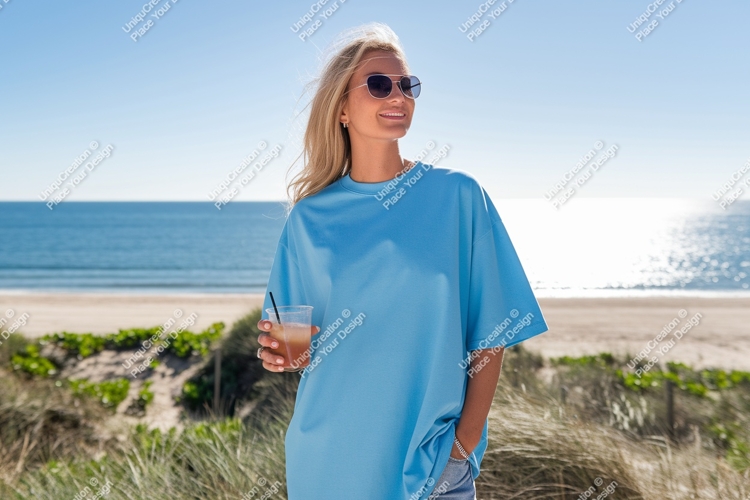 Woman wearing blue t shirt holding drink on beach image